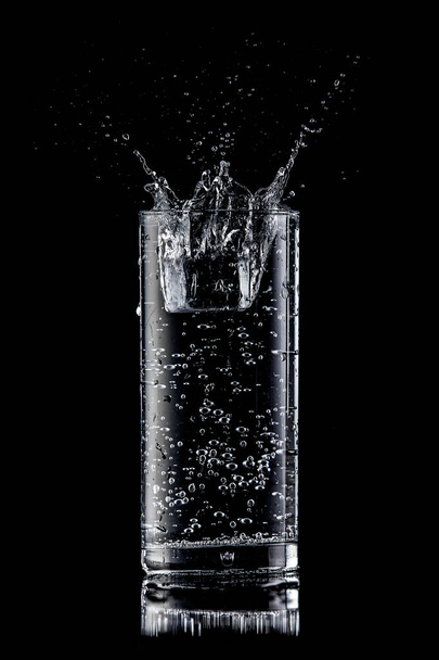 Water plons in een glas op een zwarte achtergrond - Foto, afbeelding
