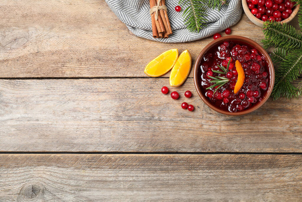 Flat lay composition with cranberry sauce on wooden table, space for text - Fotoğraf, Görsel