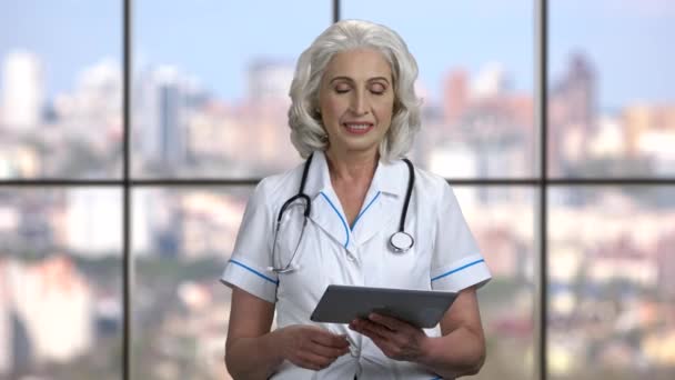 Зрелая женщина-врач с помощью цифрового планшета. - Кадры, видео