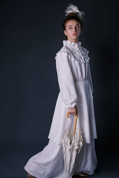 stylish retro portrait of a teenage girl in a white dress. studio. dark background - 写真・画像