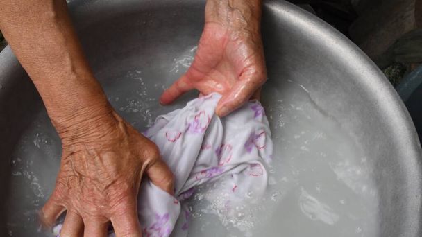 80 yaşındaki yaşlı bir kadının yaşlı, buruşuk elleriyle çamaşır yıkıyor. - Fotoğraf, Görsel