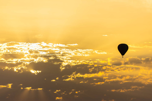 un globo de aire caliente en el cielo con nubes naranjas del amanecer - Foto, Imagen