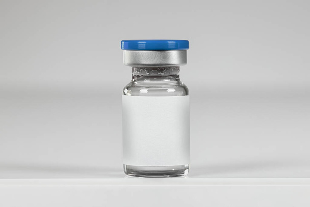 Glass ampoule of vaccine with blank label, isolated on a white background. Vial blue bottle for intramuscular injections. Vaccination, medical concept. - Zdjęcie, obraz