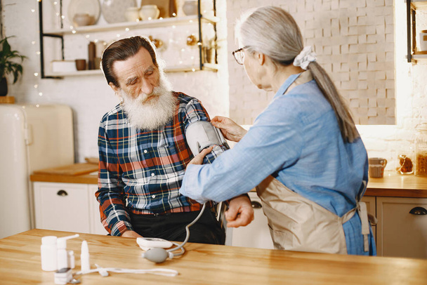 Senior woman and man at home meassure blood pressure - Photo, image