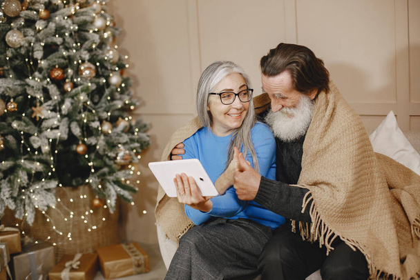 Senior couple with gifts near the Christmas tree - Photo, image
