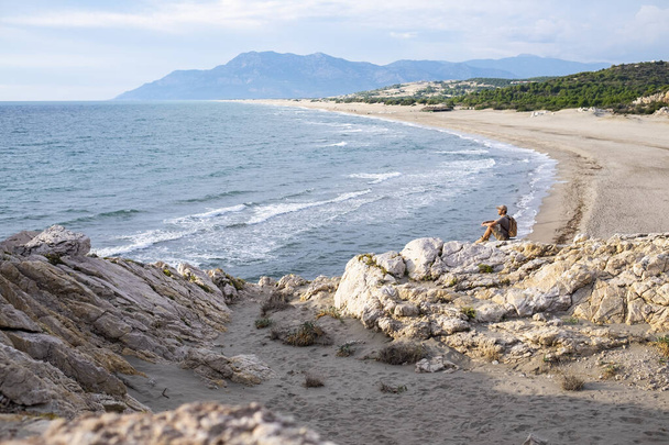 Patara beach, Southern Turkey. Man sitting on rock. - Foto, Imagen