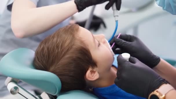 Dos doctores en gorra médica en la clínica dental, sirven al niño pequeño paciente - Metraje, vídeo
