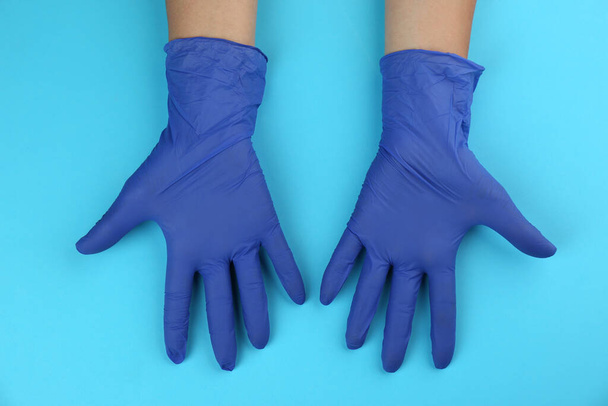 Person in medical gloves on light blue background, top view - Fotó, kép