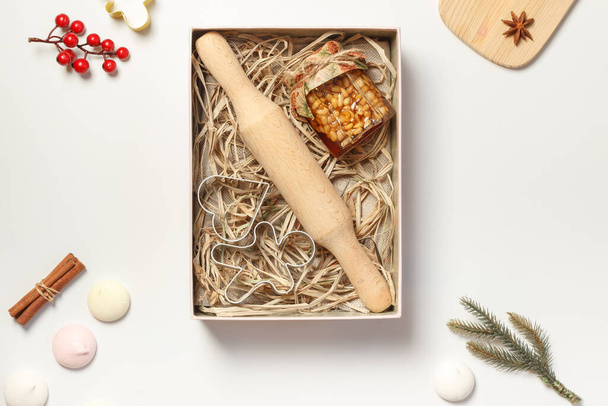 A jar of honey with pine nuts, accessories for baking cookies and gingerbread in a gift box, gift packaging for delivery. Holiday gifts in an open box - Photo, Image