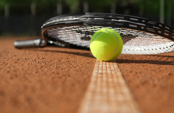 Tennis ball and racket on clay court, closeup - Fotoğraf, Görsel