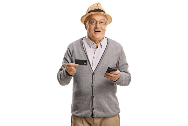 Elderly man holding a mobile phone and a credit card isolated on white background - Valokuva, kuva
