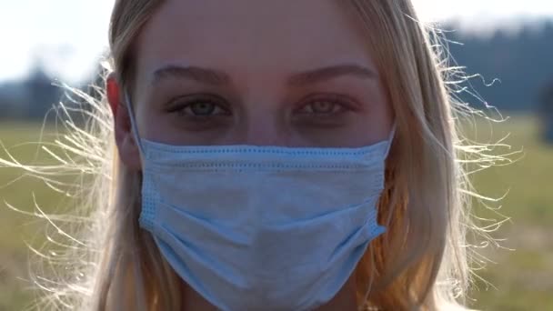 vrouw draagt een chirurgisch masker kijkend naar camera - Video