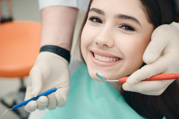 Happy brunette looking at the camera next to which medical devices. Portrait of a girl at a dentist appointment - 写真・画像