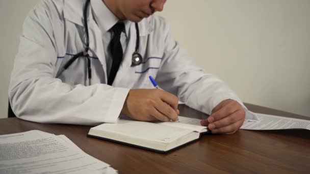 médecin garde la documentation assise à la table dans son bureau - Séquence, vidéo