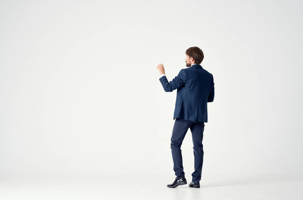 Gentleman v modrém obleku gesta s rukama na lehkém pozadí pohled zpět obchodní finance - Fotografie, Obrázek