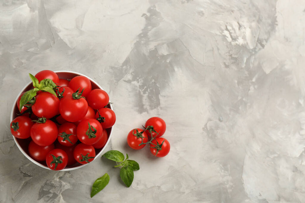 Fresh ripe cherry tomatoes and basil on light grey table, flat lay. Space for text - Foto, immagini