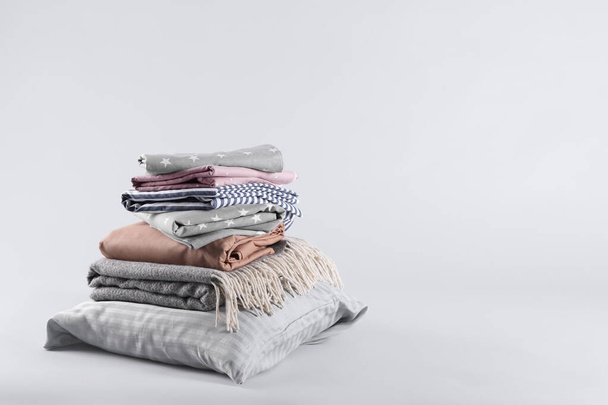 Stack of clean bed sheets and pillow on white background. Space for text - Fotó, kép