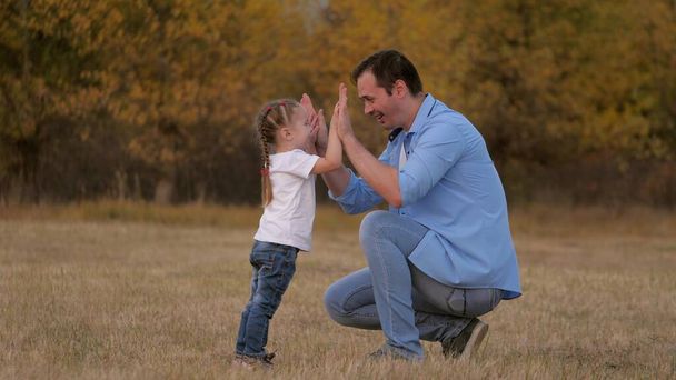 Papa joue avec sa petite fille apprend à serrer la main, bonjour papa. Père et enfant bien-aimé s'amusent ensemble. Joyeux concept de famille. Les enfants et les parents s'amusent dans le parc. Marcher à l'extérieur - Photo, image
