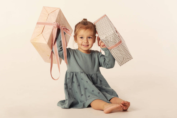 aranyos kis szőke lány kék ruha karácsonyi ajándék doboz közelkép fotó elszigetelt fehér - Fotó, kép