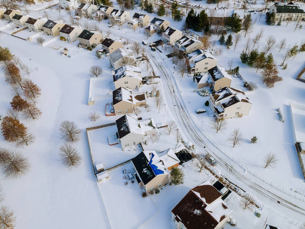 Letecký pohled na obytné domy pokryté sněhem na krytých domech a silnicích v zimní sezóně - Fotografie, Obrázek