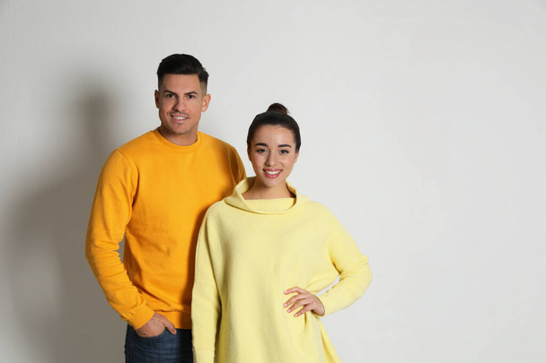 Happy couple wearing yellow warm sweaters on white background. Space for text - Фото, зображення