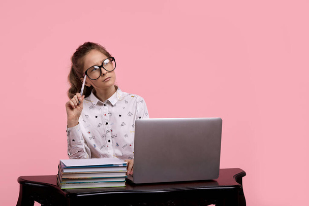 dziewczyna w bluzce trzyma w ręku okulary w czarnej ramce siedzi przy komputerze - Zdjęcie, obraz