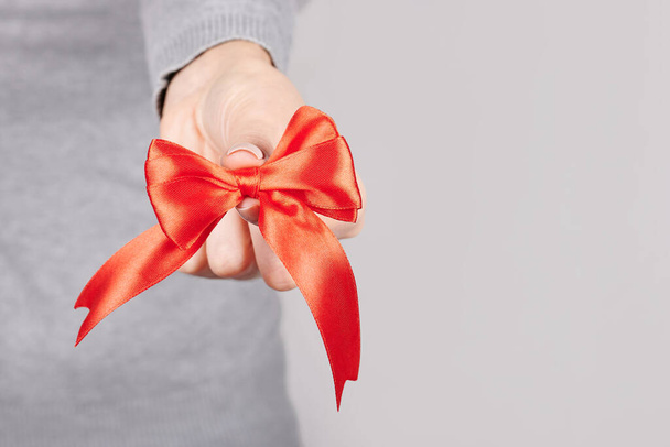 Hand with red ribbon on grey. - Photo, Image