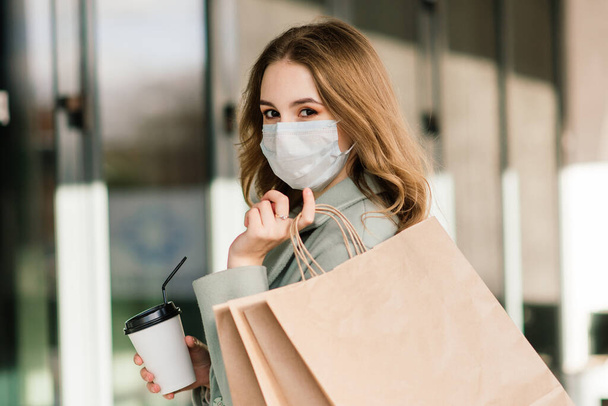 Avrupa 'nın dar sokaklarında alışveriş torbaları taşıyan virüsü önlemek için maske takan genç bir kadın.. - Fotoğraf, Görsel