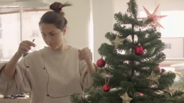 Cabello oscuro mezcla raza hembra decoración y artificial árbol de Navidad en casa. Cámara de tamaño mediano 4k filmación de vídeo de alta calidad. - Metraje, vídeo