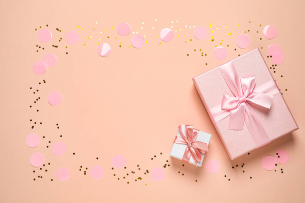 Frame of shiny confetti and beautiful gift boxes on color background, flat lay. Space for text - Foto, immagini