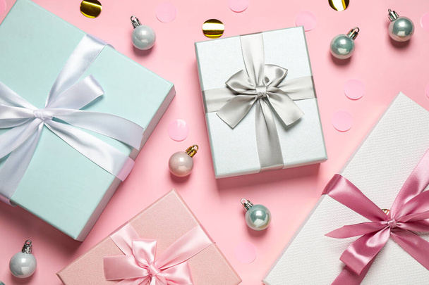 Beautiful gift boxes, Christmas balls and confetti on pink background, flat lay - Fotoğraf, Görsel
