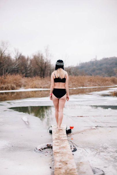 Young slender girl bathes in winter in a river hole - Foto, Bild