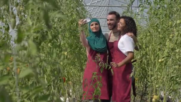 Jardineros alegres y diversos tomando selfie en invernadero - Imágenes, Vídeo