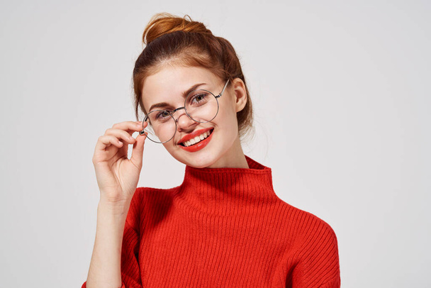 Hübsche Frau im roten Pullover gestikuliert mit Händen und Brille auf Make-up-Modell - Foto, Bild
