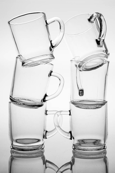 Thick glass mugs stacked. Drinking water storage containers. Light background. - Foto, imagen