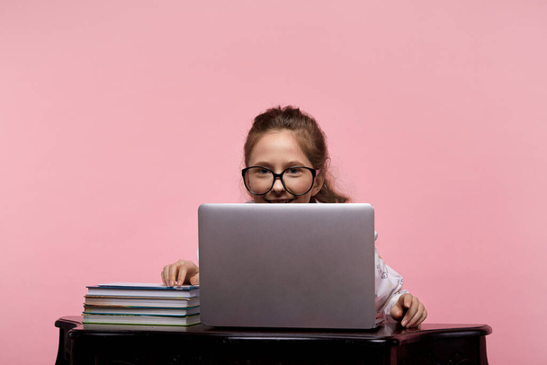 Girl in a blouse and blue jeans in glasses in a black rim sitting at a computer - Foto, Imagem