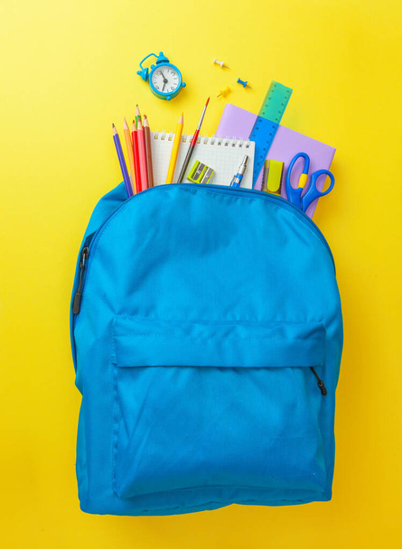 Un cartable. Sac à dos avec fournitures pour l'école sur fond jaune. Espace de copie pour le texte - Photo, image