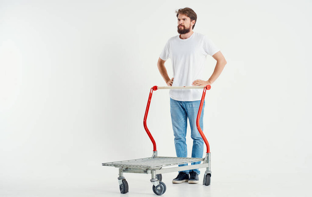 a man in a cargo trolley on a light background superhero transporting heavy objects - Foto, afbeelding