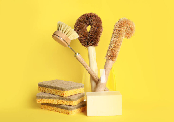 Cleaning supplies for dish washing on yellow background - Foto, Bild