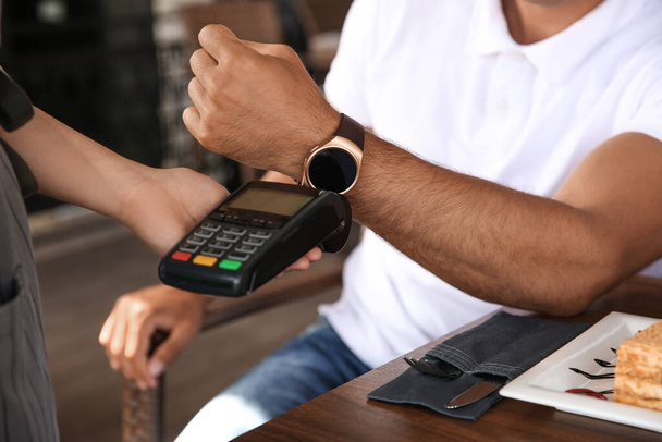 Man making payment with smart watch in cafe, closeup - Fotó, kép
