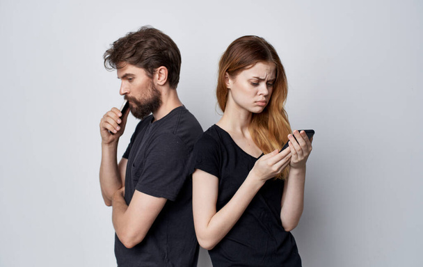 young couple in black t-shirts with phones in hands communication internet technology - Valokuva, kuva