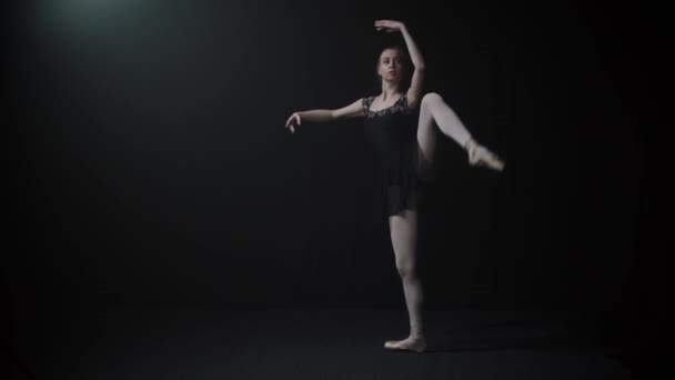 Giovane donna graziosa ballerina in abito nero che balla lentamente sulle punte dei piedi - Filmati, video