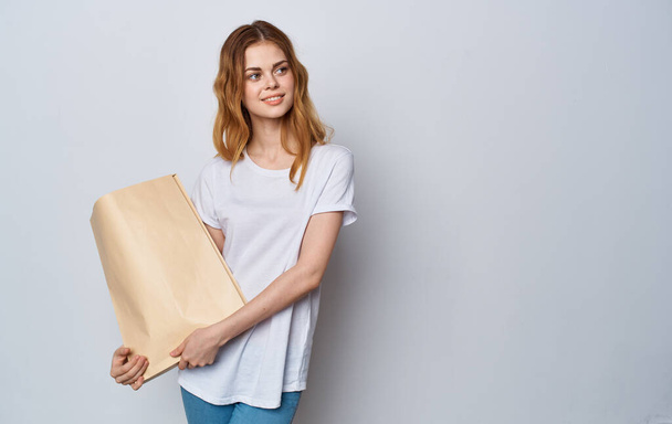 Iloinen nainen valkoisessa T-paidassa paketti kädessään Ostokset - Valokuva, kuva