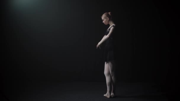Νεαρή χαριτωμένη γυναίκα μπαλαρίνα σε μαύρο φόρεμα αργά χορό σε μαύρο στούντιο - Πλάνα, βίντεο