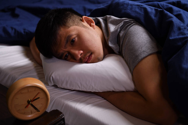 Ein depressiver junger Mann, der an Schlaflosigkeit leidet, sitzt im Bett - Foto, Bild