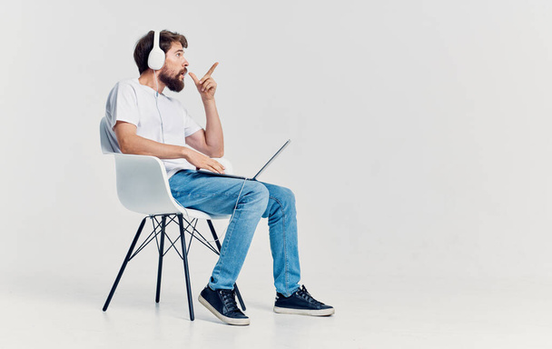 άνθρωπος με ακουστικά μπροστά από το laptop κάθεται σε καρέκλα γραφείο τεχνολογίας επικοινωνίας - Φωτογραφία, εικόνα