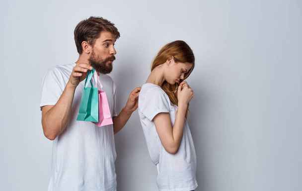 donna offesa allontanata da un uomo con borse regalo su uno sfondo leggero - Foto, immagini