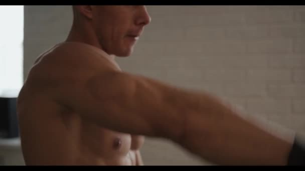 Jeune bodybuilder avec un entraînement de torse nu dans la salle de gym et faire de l'exercice avec des haltères sur le muscle deltoïde - Séquence, vidéo