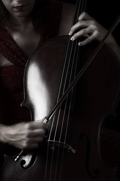 Красива брюнетка грає на віолончелі з вибірковим світлом у червоному сні
 - Фото, зображення