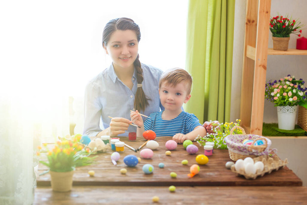 Charming mother and son celebrating Easter. Family celebrating Easter. Parent and kid play indoors. Decorated home and spring flowers. - Φωτογραφία, εικόνα